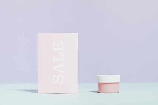 Elegant still life of a sale card and cream jar on pastel background.