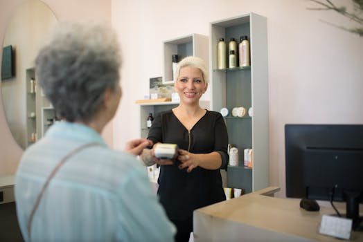 Friendly hairdresser assisting customer with payment in a stylish salon setting.