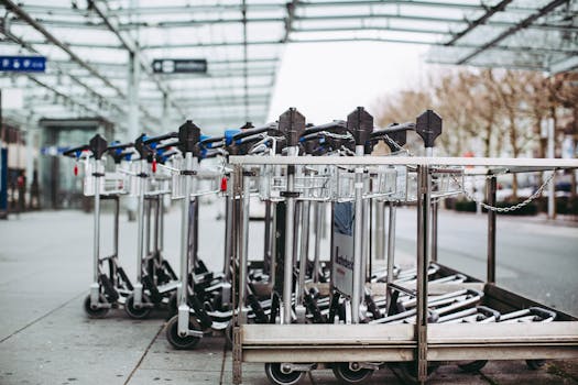 Row of luggage carts lined up outdoors at an airport terminal on a clear day.
