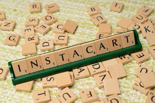 Wooden Scrabble tiles spelling 'INSTACART' on a green holder with scattered tiles.